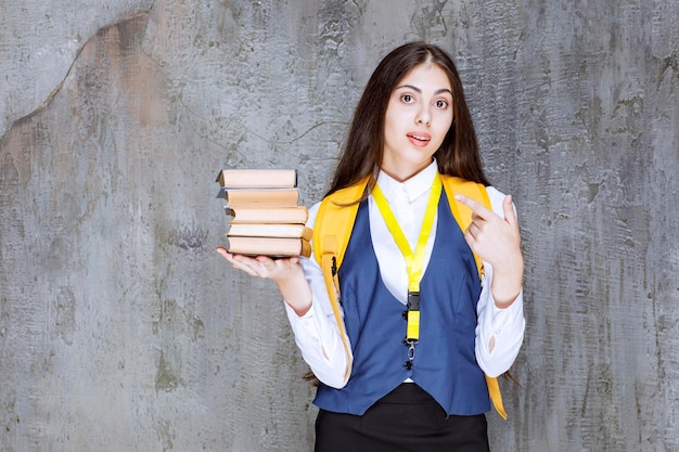Aufnahme einer langhaarigen Studentin mit stehenden Büchern. Foto in hoher Qualität