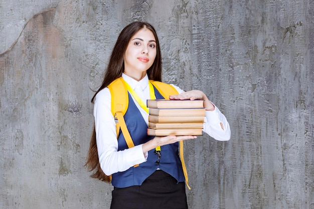 Aufnahme einer langhaarigen Studentin mit stehenden Büchern. Foto in hoher Qualität