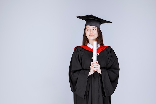 Aufnahme eines Doktoranden im Kleid mit College-Zertifikat posiert. Foto in hoher Qualität