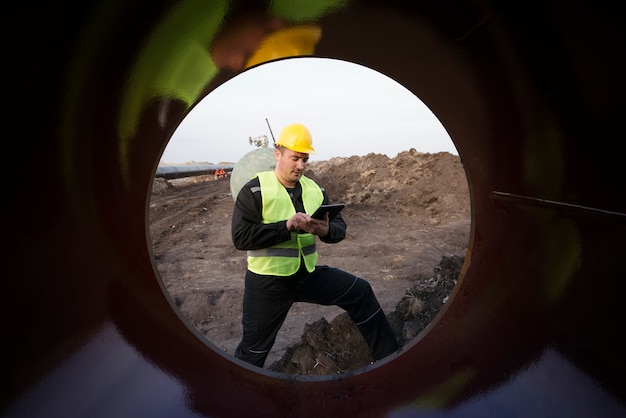 Aufnahme eines Ölfeldarbeiters, der die Qualität der Gasleitungen auf der Baustelle überprüft