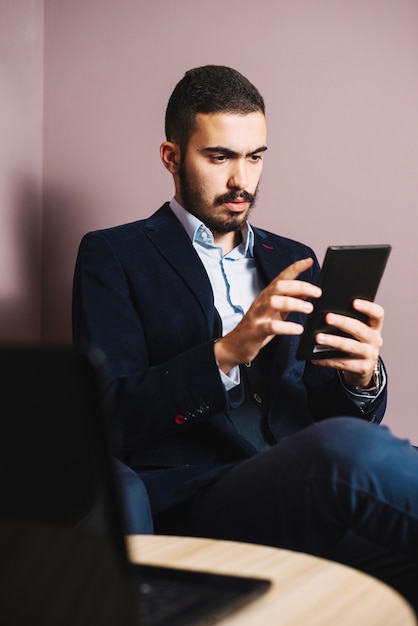 Aufpassende Tablette des hübschen Geschäftsmannes