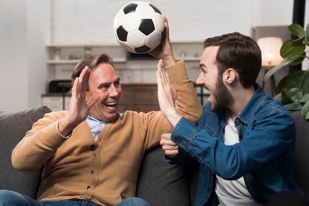 Aufpassender Sport des Vaters und des Sohns und Zujubeln im Wohnzimmer