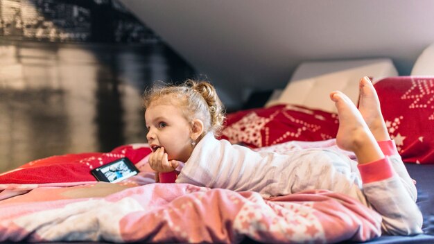 Aufpassendes Video des netten Mädchens auf Bett