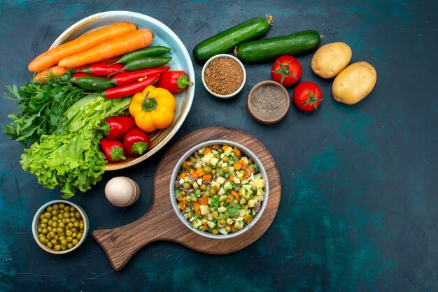 Aufschnitt geschnittener Gemüsesalat mit Hühnerscheiben in Teller mit frischem Gemüse auf dem dunkelblauen Schreibtisch