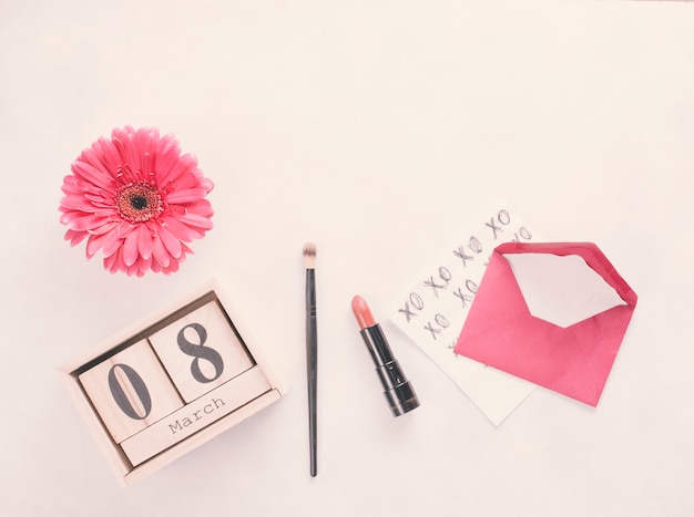 Aufschrift des 8. März auf Holzklötzen mit Blume und Lippenstift auf Tabelle