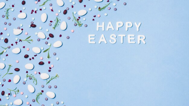 Aufschrift fröhliche Ostern verziert durch Dragees und Blumen