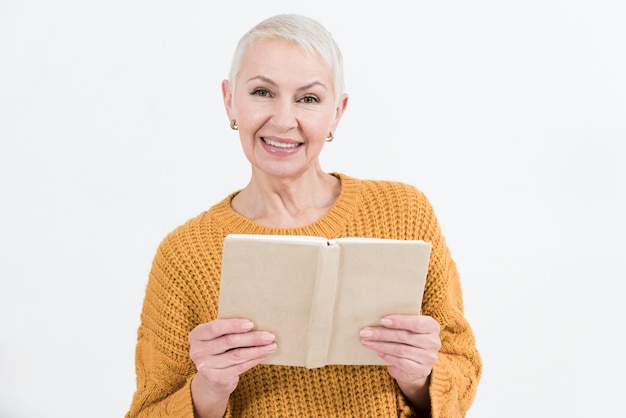 Aufwerfende ältere Frau des smiley beim Halten des Buches