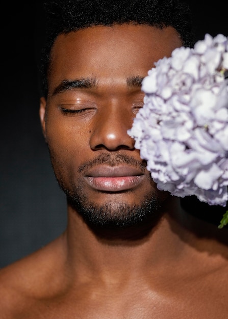 Kostenloses Foto ausdrucksstarker mann der nahaufnahme, der mit blumen aufwirft