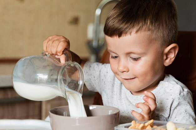 Auslaufende Milch des glücklichen Kindes in einer Schüssel
