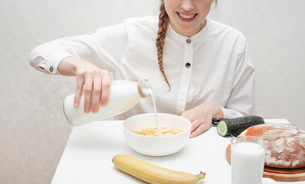 Auslaufende Milch des netten Mädchens in einer Schüssel mit Getreide