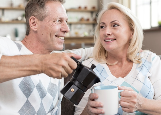 Auslaufender Kaffee des glücklichen Mannes des mittleren Schusses zur Frau