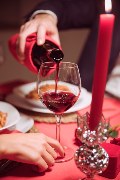 Auslaufender Wein des Mannes im Glas auf festlicher Tabelle