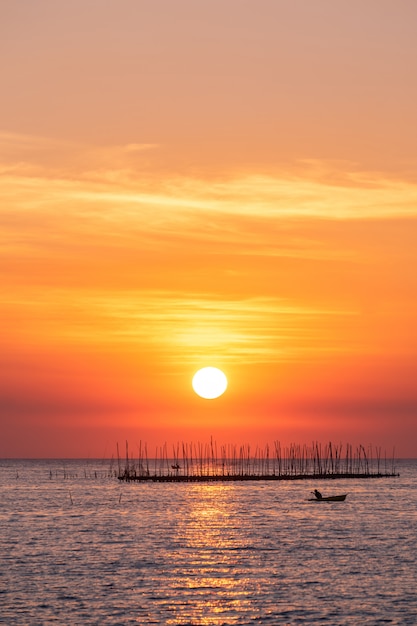 Austernbauernhof im Sonnenunterganghintergrund des Meeres und des schönen Himmels