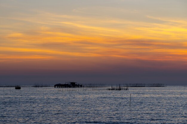 Austernbauernhof im Sonnenunterganghintergrund des Meeres und des schönen Himmels