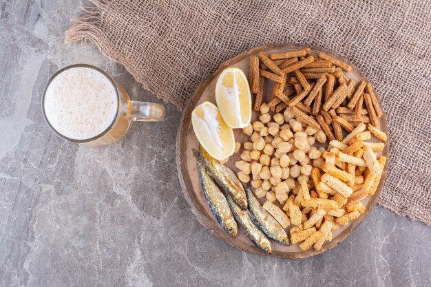 Auswahl an leckeren Snacks auf Holzstück mit Bier. Foto in hoher Qualität