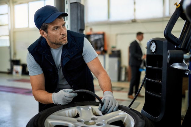 Automechaniker, der den Reifendruck während der Arbeit in der Autowerkstatt anpasst