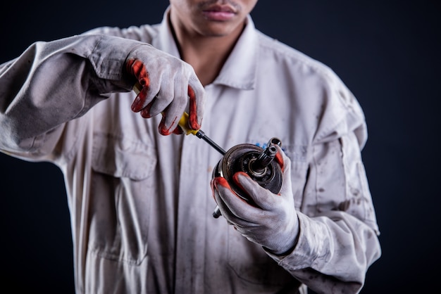 Automechaniker, der einen weißen einheitlichen Stand hält Schlüssel trägt