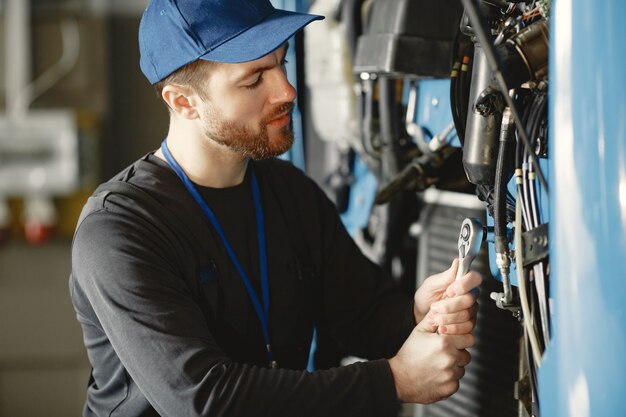 Automechaniker repariert blaues Auto in der Garage mit Werkzeugen