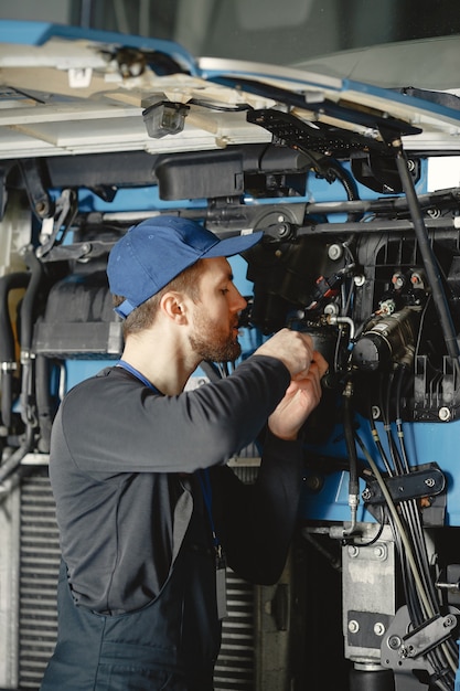 Kostenloses Foto automechaniker repariert blaues auto in der garage mit werkzeugen