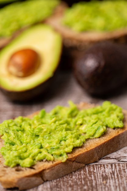 Avocado-Sandwiches neben geschnittenen auf Holzbrett.