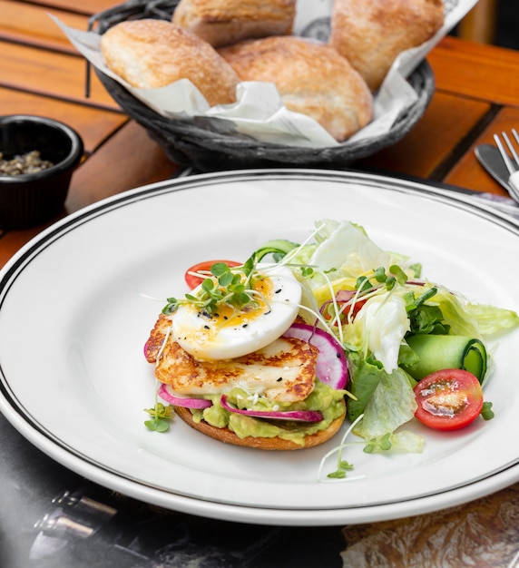 Avocado-Toast mit Radieschen, Syrniki und gekochtem Ei, serviert mit frischem Salat