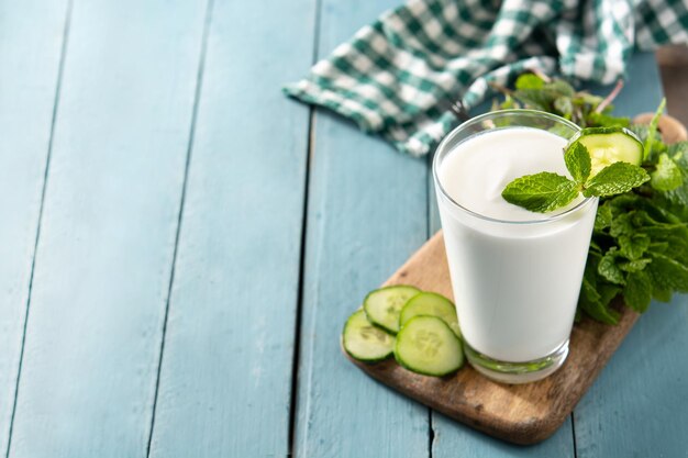 Ayran-Getränk mit Minze und Gurke im Glas auf blauem Holztisch