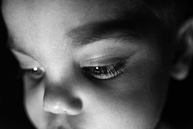 Baby auf schwarzem Hintergrund mit Licht, das auf seinem Gesicht reflektiert