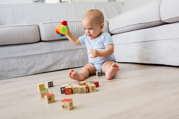 Baby, das auf dem Boden sitzen und mit Spielzeug im Wohnzimmer spielen