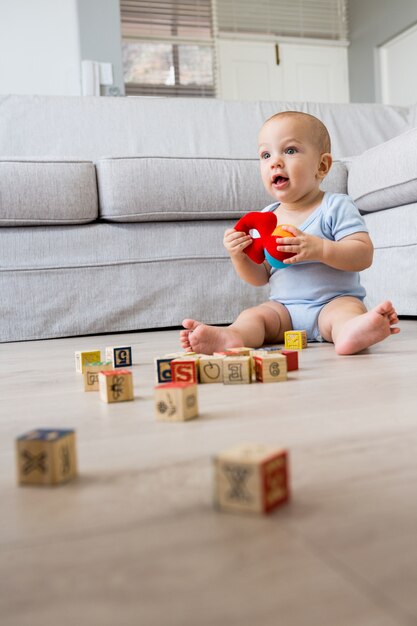 Baby, das auf dem Boden sitzen und mit Spielzeug im Wohnzimmer spielen