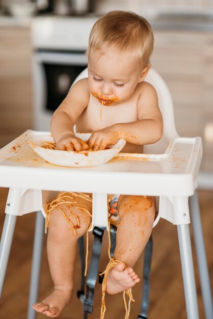 Baby, das ein Durcheinander mit Nudeln macht