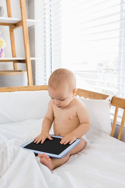Baby, das mit digitalen Tablette auf einer Wiege spielen