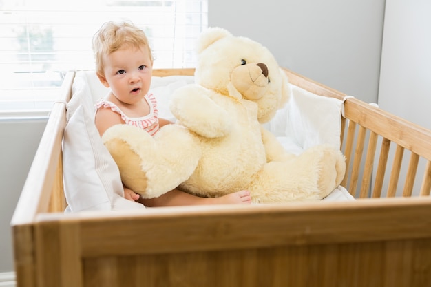 Baby, das mit einem Teddybären spielt in einer Wiege