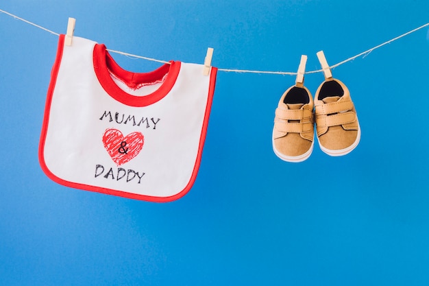Baby-Konzept mit Lätzchen und Schuhe hängen an Wäscheleine