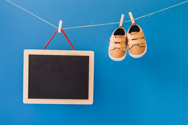 Baby-Konzept mit Schiefer und Schuhe auf Wäscheleine