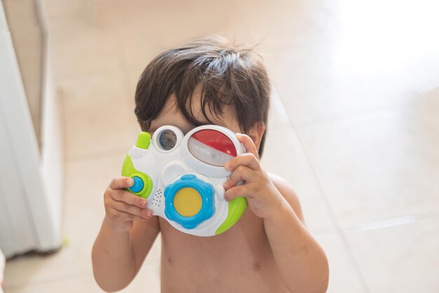Babyjunge, der Fotos mit Spielzeugkamera macht