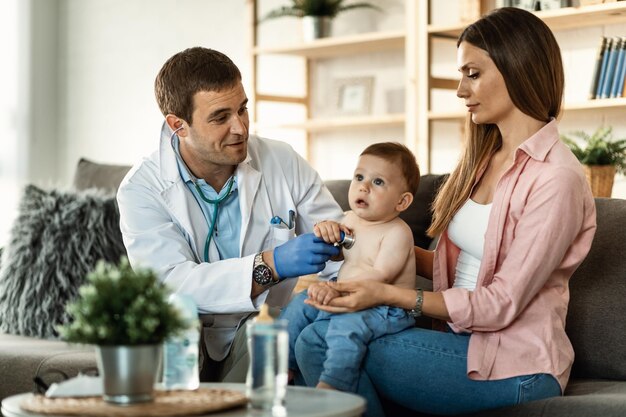 Babyjunge mit ärztlicher Untersuchung durch männlichen Kinderarzt, während er bei seiner Mutter ist Fokus liegt auf Arzt