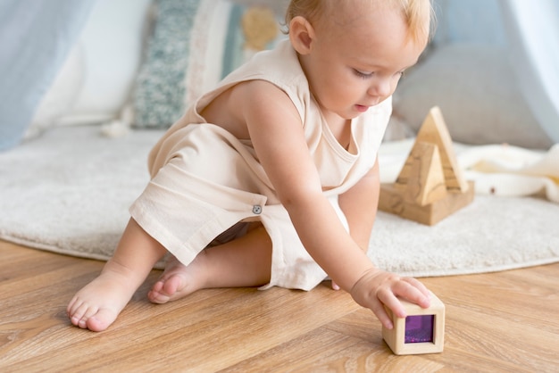 Babymädchen, das mit einem Holzklotz spielt