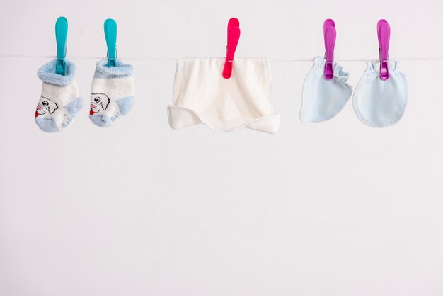 Babyunterwäsche und -hut, die auf Wäscheleine trocknen