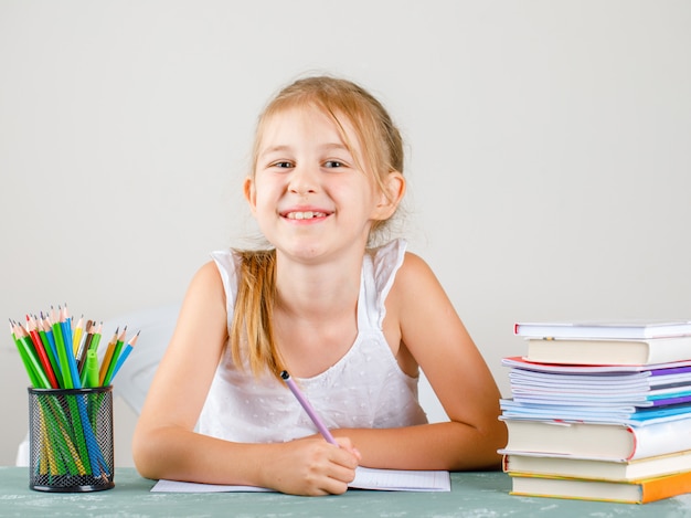 Back to School-Konzept mit Bleistiften, Büchern, Heften Seitenansicht. kleines Mädchen mit Bleistift.