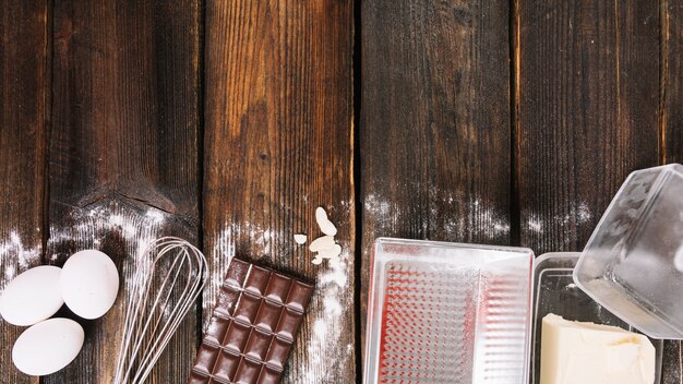 Backende Kuchenzutaten mit Küchengerät auf hölzerner Planke