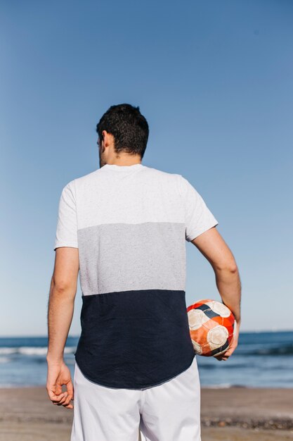 Kostenloses Foto backview des mannes mit fußball am strand