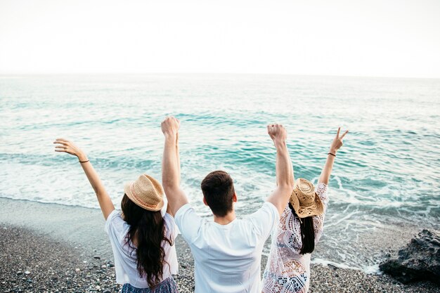 Backview von Freunden am Strand, der Arme anhebt