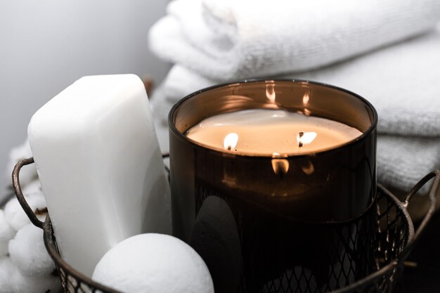 Badezubehör und eine brennende Kerze in einem Korb. Aromatherapie-Konzept.