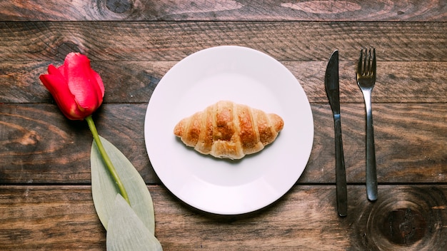 Kostenloses Foto bäckerei auf platte in der nähe von blumen und besteck