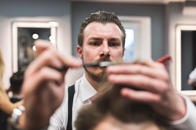 Bärtiger Friseur, der Haar des Kunden schneidet