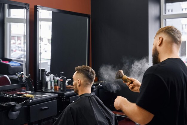 Bärtiger Mann, der im Friseursalon sitzt und sich die Haare schneiden lässt