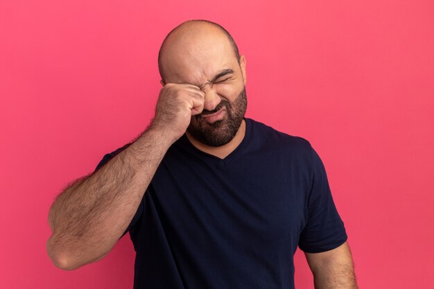 Kostenloses Foto bärtiger mann im marine-t-shirt, das müde aussieht, will schlafen reiben auge über rosa wand stehen