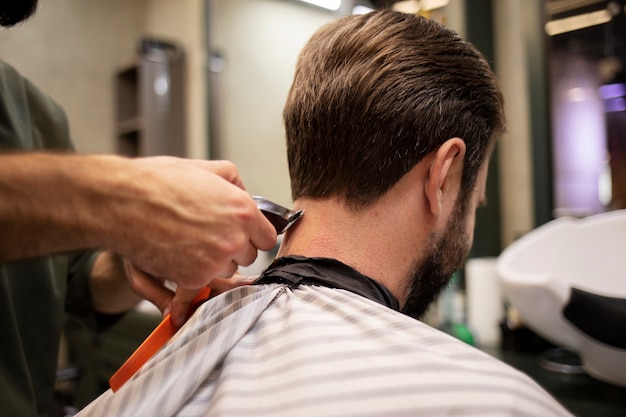 Bärtiger Mann lässt sich beim Friseur die Haare schneiden