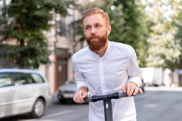 Bärtiger moderner Mann der Vorderansicht auf Roller außerhalb