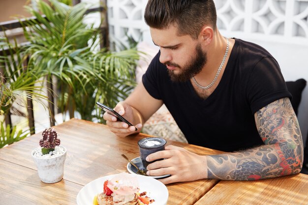 Bärtiger stilvoller Mann, der im Café sitzt